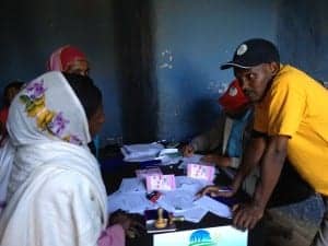 Ethiopia MFI staff discussing savings account with girl saver in Lumame