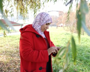 Women in red coat stares at mobile phone.