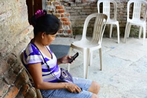 Woman in purple shirt looks at mobile phone.