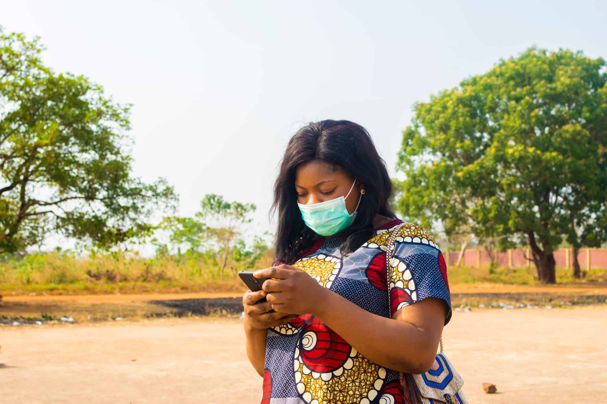 Woman in colorful shirt looks at mobile phone.