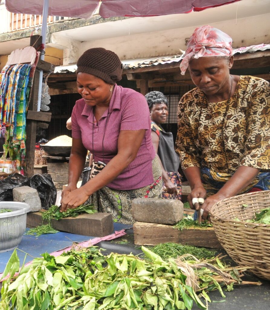 Ime, pictured on the left, grew her open-market business and is now able to send all six of her children to school thanks to a savings solution developed in partnership with a retail bank in Nigeria.  