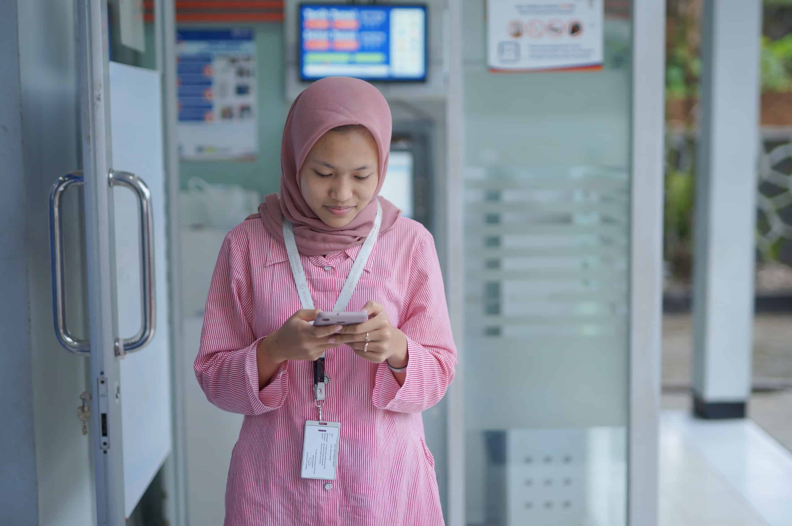 Southeast Asian woman using financial services on her smartphone, highlighting the importance of inclusive fintechs